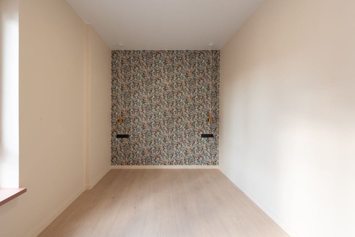Empty room with a single patterned wallpaper feature wall and wall lights