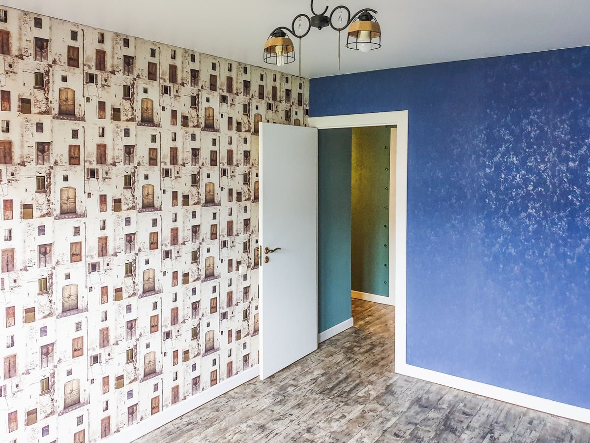 Room combining a patterned wallpaper wall with a painted blue accent wall