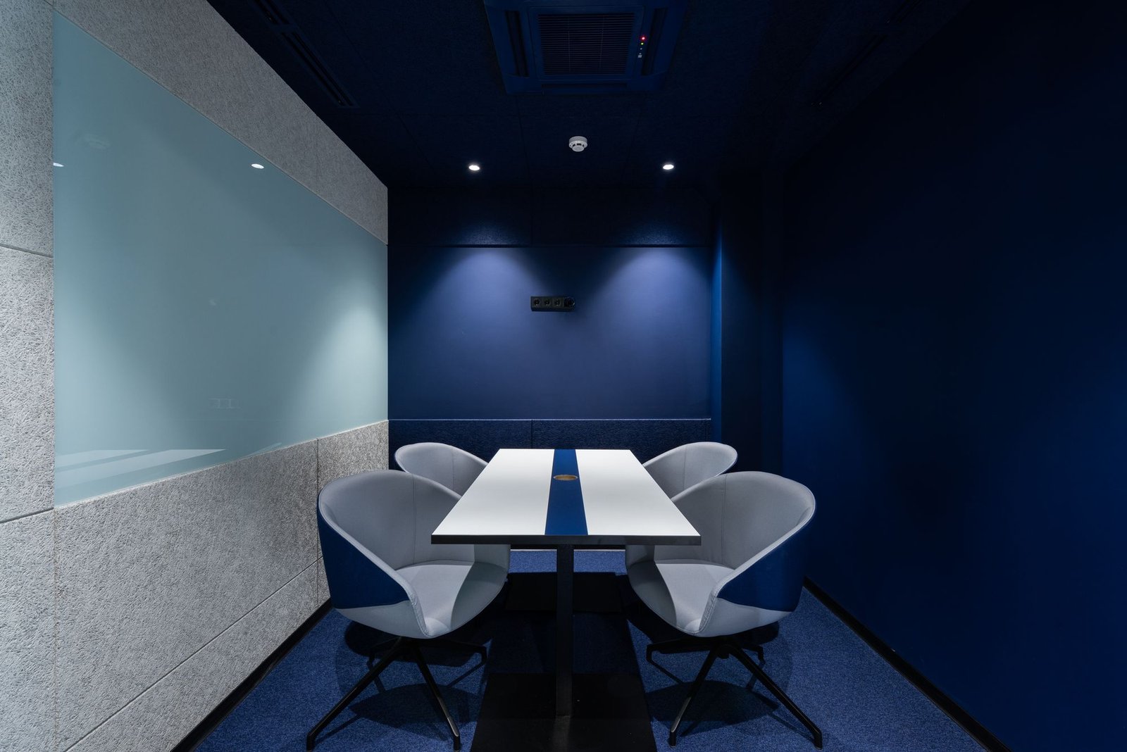 Meeting room with a deep navy accent wall, glass partition, and modern chairs