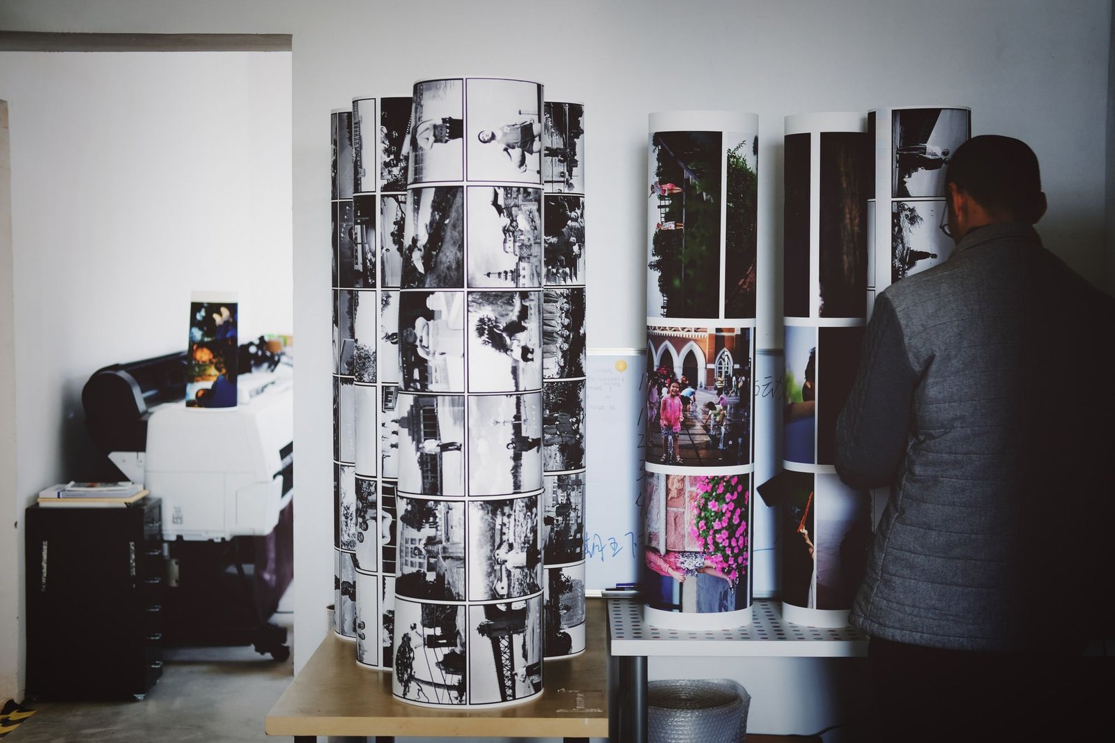 Print studio with tall rolls of large-format photo prints beside a wide-format printer