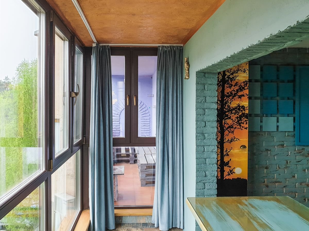 Enclosed balcony with a printed sunset-tree photo mural on one wall