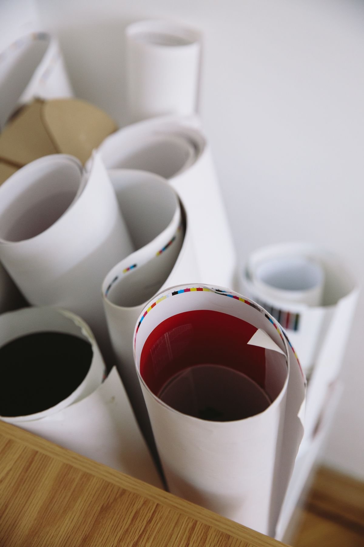 Rolled printed sheets with colour-bar edges on a wooden table