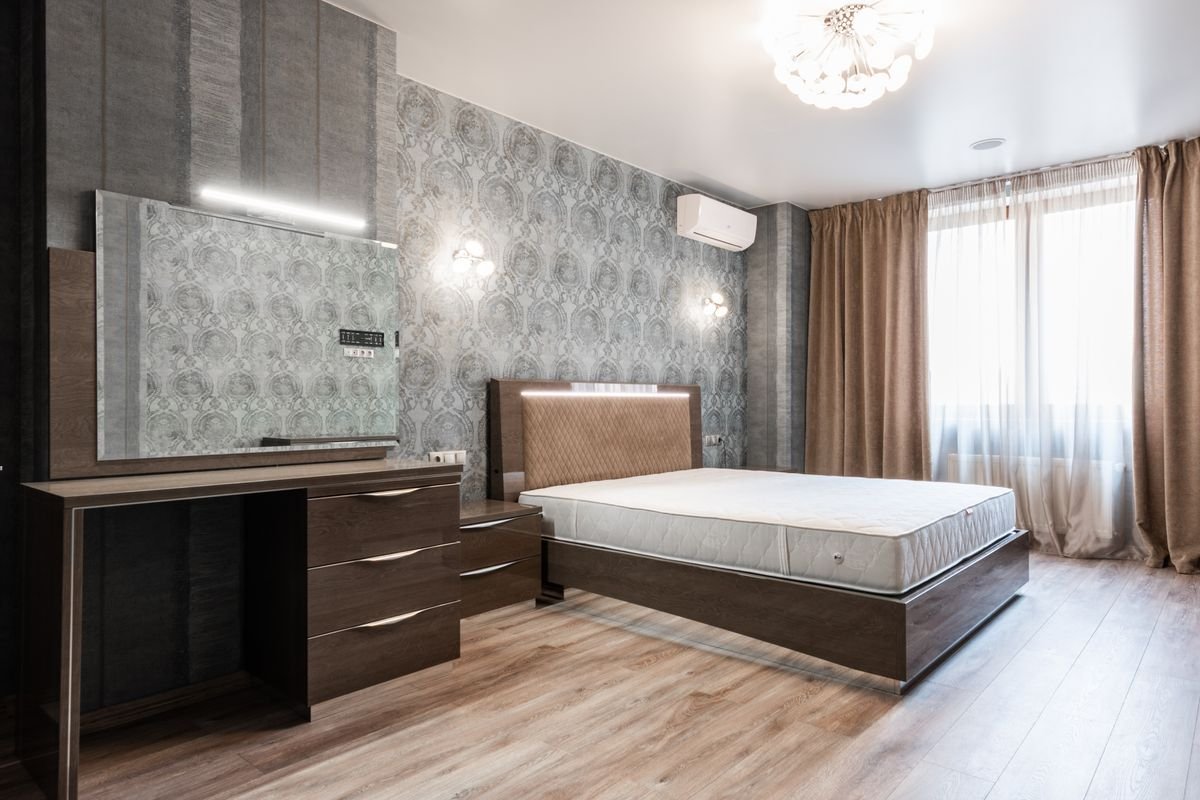 Bedroom with grey patterned wallpaper behind the bed and dressing table