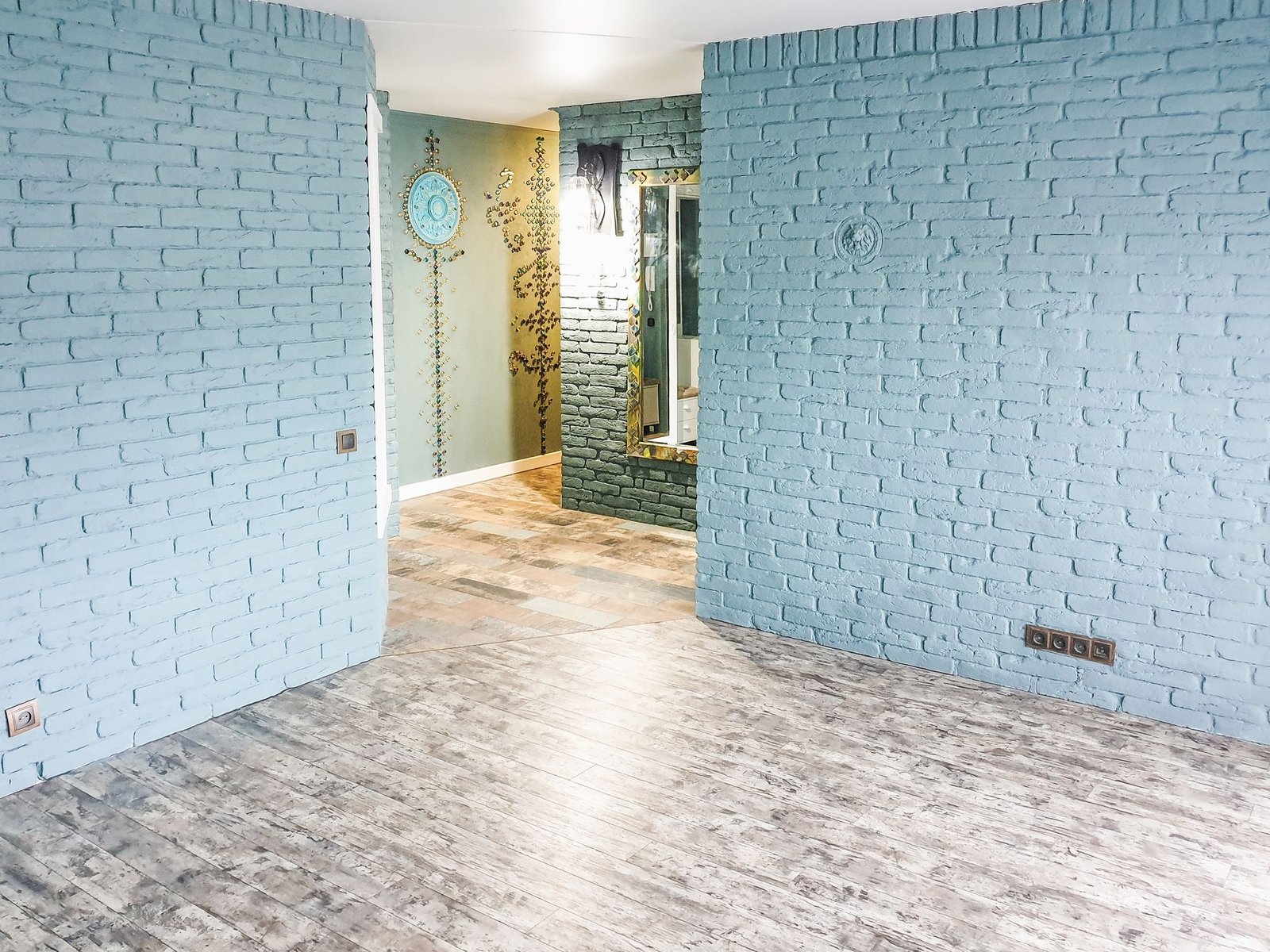Room with blue-grey brick-effect feature walls and a wooden floor