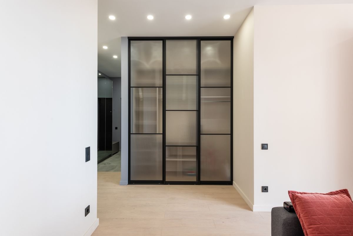 Room with clean smooth walls and black-framed glass doors ready for new finishes